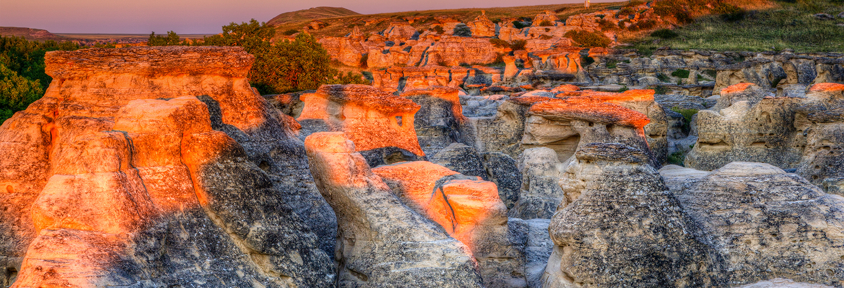 Sunrise shining over the Hoodoo badlands at Writing-on-Stone Provincial Park in Alberta, Canada.