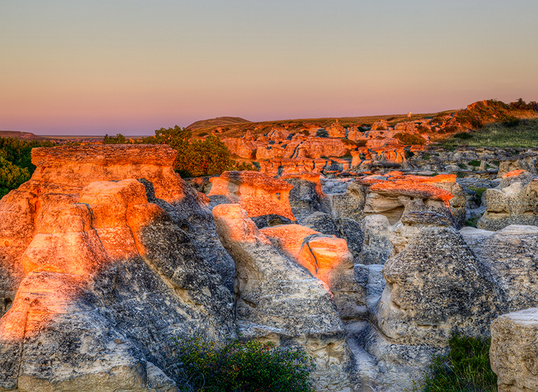 Sunrise shining over the Hoodoo badlands at Writing-on-Stone Provincial Park in Alberta, Canada.