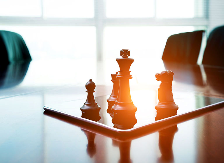 Chess pieces standing on a digital tablet