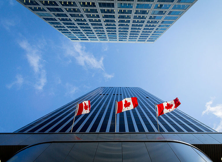 Three Canadian flags in front of a business building